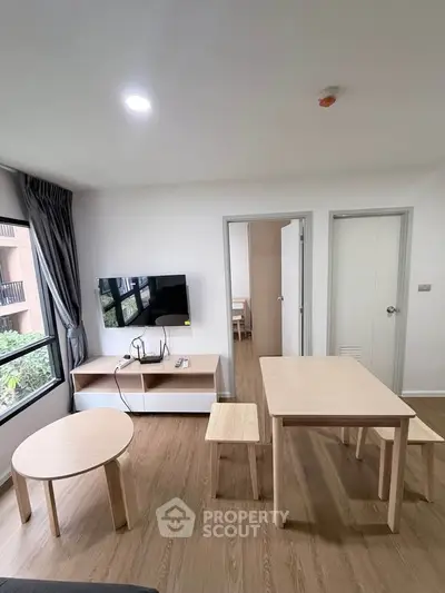 Modern living room with wooden furniture and wall-mounted TV in a bright apartment.