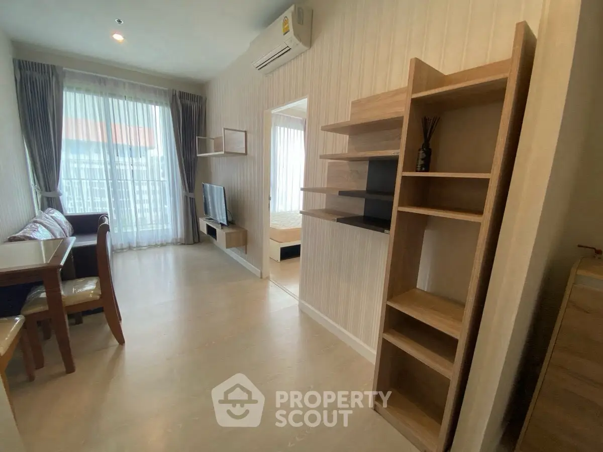 Modern apartment interior with open living and dining area, featuring stylish shelving and natural light.