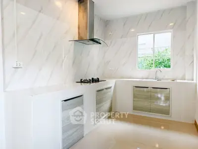 Modern kitchen with sleek design and gas stove, featuring marble walls and ample natural light.