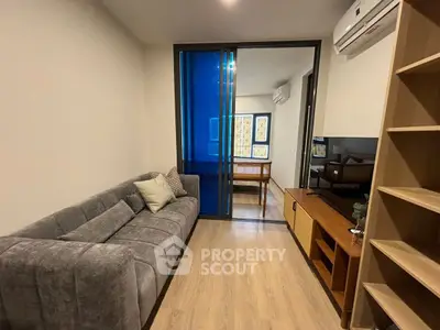 Modern living room with sleek sofa and TV, featuring a stylish partition and air conditioning.