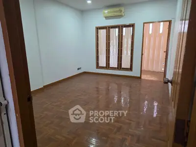 Spacious empty room with polished wooden flooring and large windows, ideal for customization.