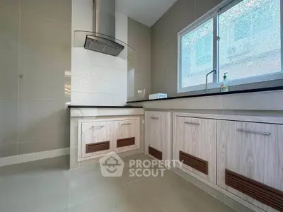 Modern kitchen with sleek cabinetry and large window, perfect for culinary enthusiasts.