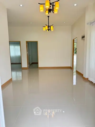 Spacious empty living room with elegant lighting and glossy tiled floors.