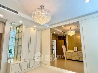 Luxurious bedroom with elegant chandelier and mirrored wardrobe in modern apartment.