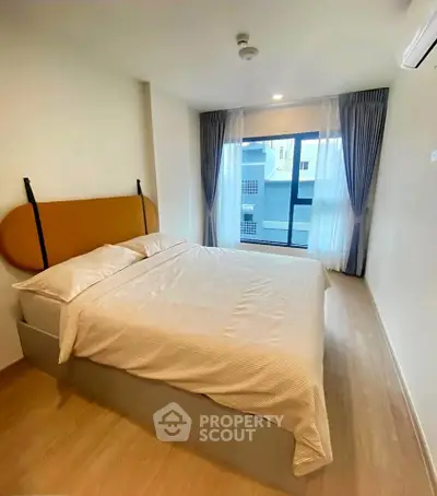 Modern bedroom with large window and stylish decor in a contemporary apartment.