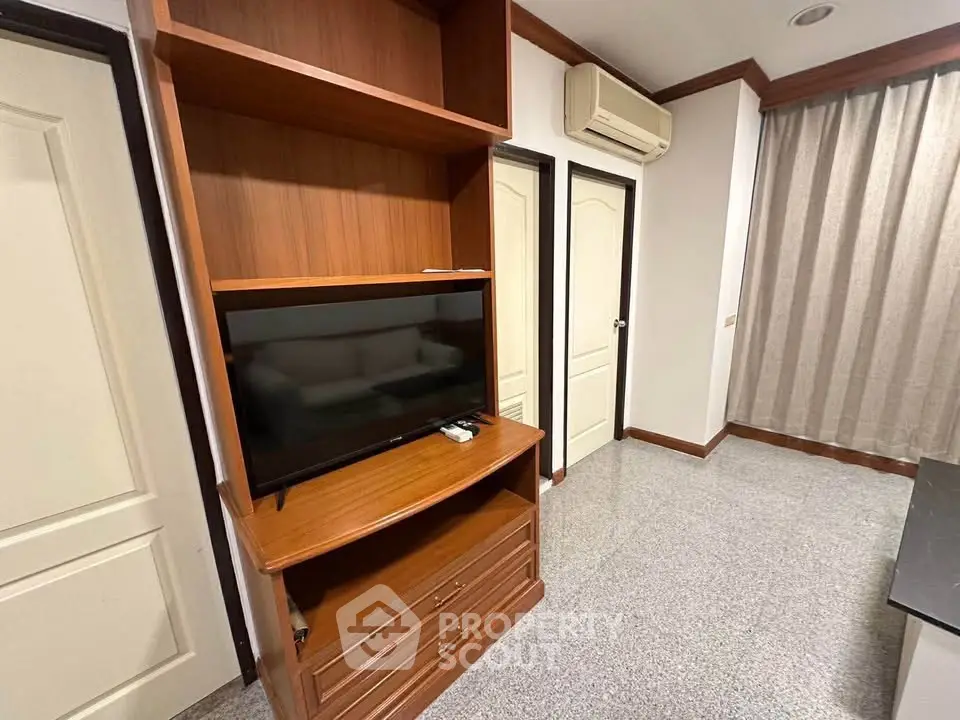 Cozy living room with built-in wooden TV cabinet and air conditioning unit.