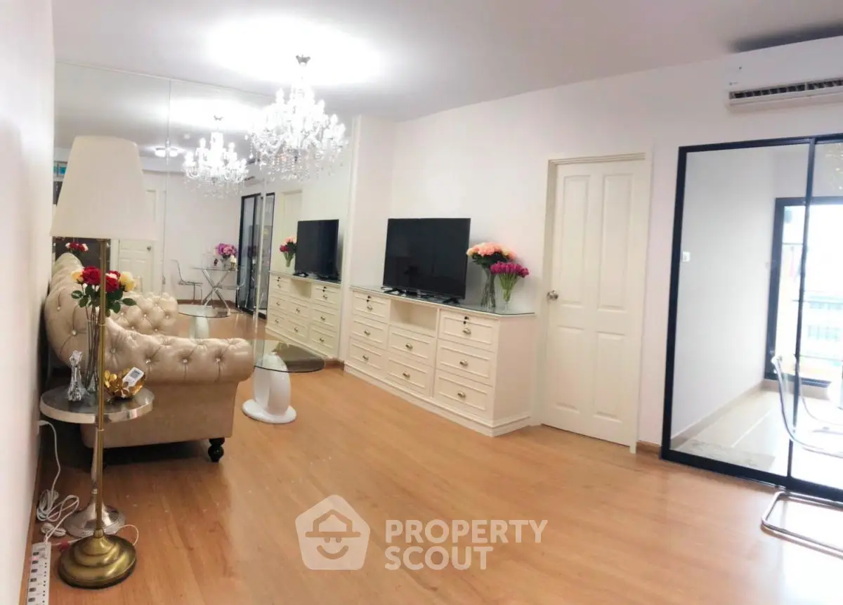 Elegant living room with chandelier and modern decor, featuring a spacious layout and stylish furniture.