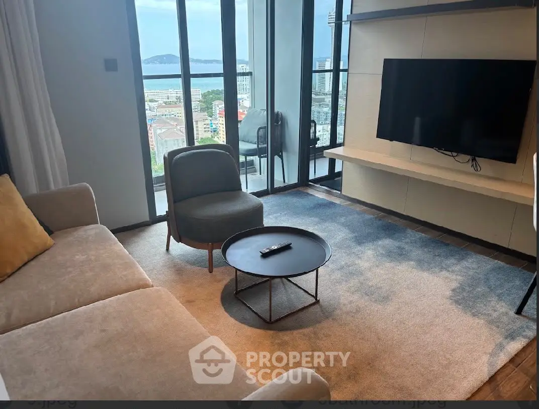 Modern living room with stunning city view, featuring cozy seating and sleek TV setup.