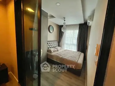 Cozy bedroom with elegant decor and natural light, featuring a plush bed and stylish chandelier.