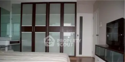Modern bedroom with sleek wardrobe and flat-screen TV, perfect for contemporary living.