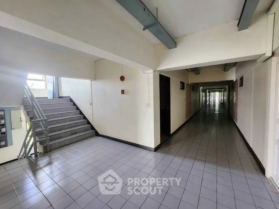 Spacious corridor with tiled flooring and staircase in modern building