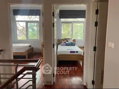 Bright and airy bedroom with wooden flooring and large windows overlooking greenery.
