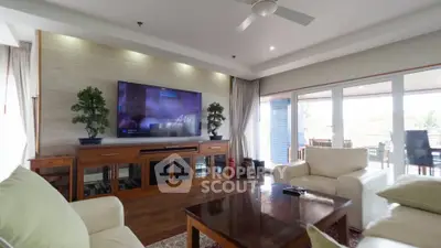 Spacious living room with modern decor and large TV, perfect for relaxation.