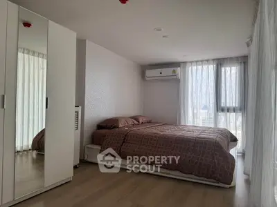 Spacious bedroom with modern decor and large windows offering city views.