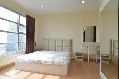 Spacious bedroom with large window offering city view and modern furnishings.