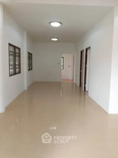 Spacious empty room with tiled flooring and bright lighting, ideal for customization.