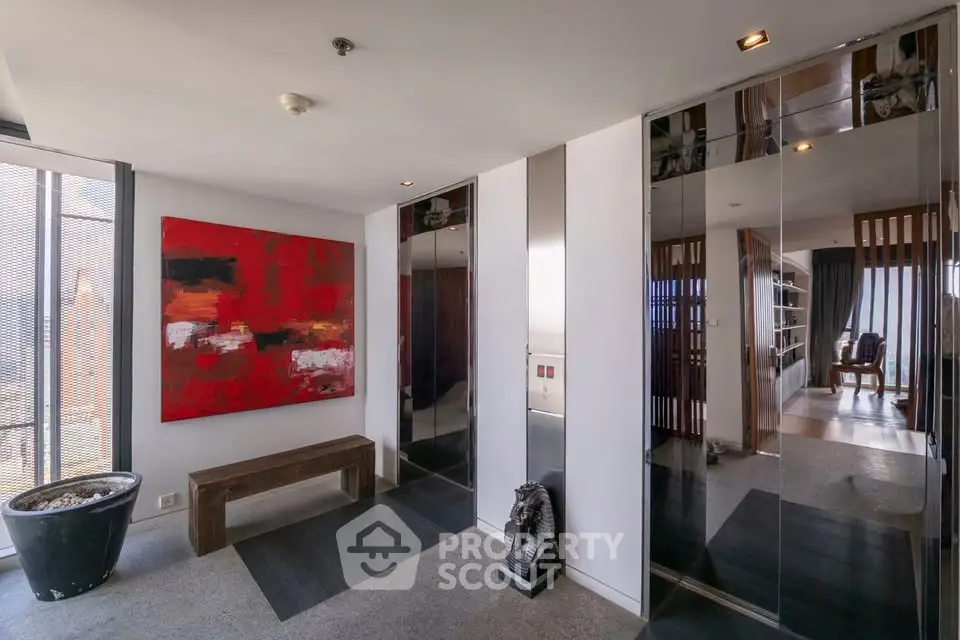 Modern apartment entrance with stylish decor and art piece, featuring sleek design and natural light.