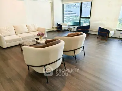 Spacious modern living room with elegant furniture and large windows offering city views.