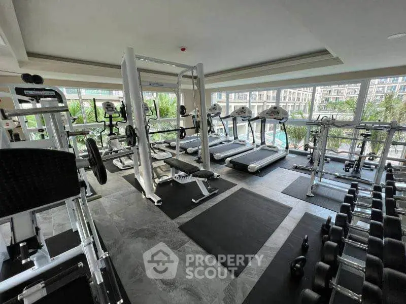 Modern gym with state-of-the-art equipment and pool view in luxury apartment complex.