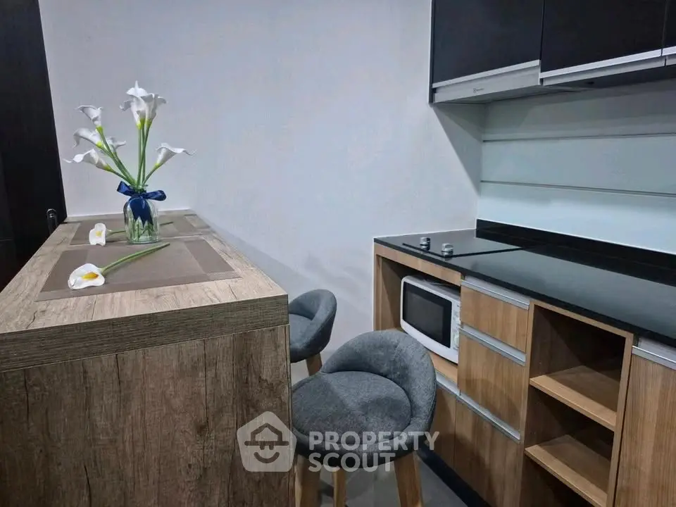 Modern kitchen with sleek cabinetry and breakfast bar, featuring a stylish microwave and elegant decor.