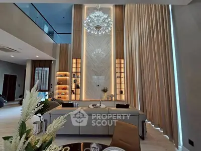 Luxurious living room with high ceilings, elegant chandelier, and modern decor