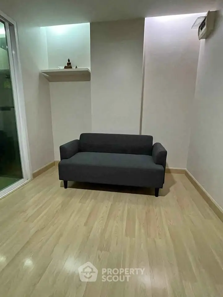 Minimalist living room with sleek sofa and wooden flooring, perfect for modern urban living.
