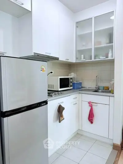 Compact modern kitchen with white cabinets and stainless steel appliances