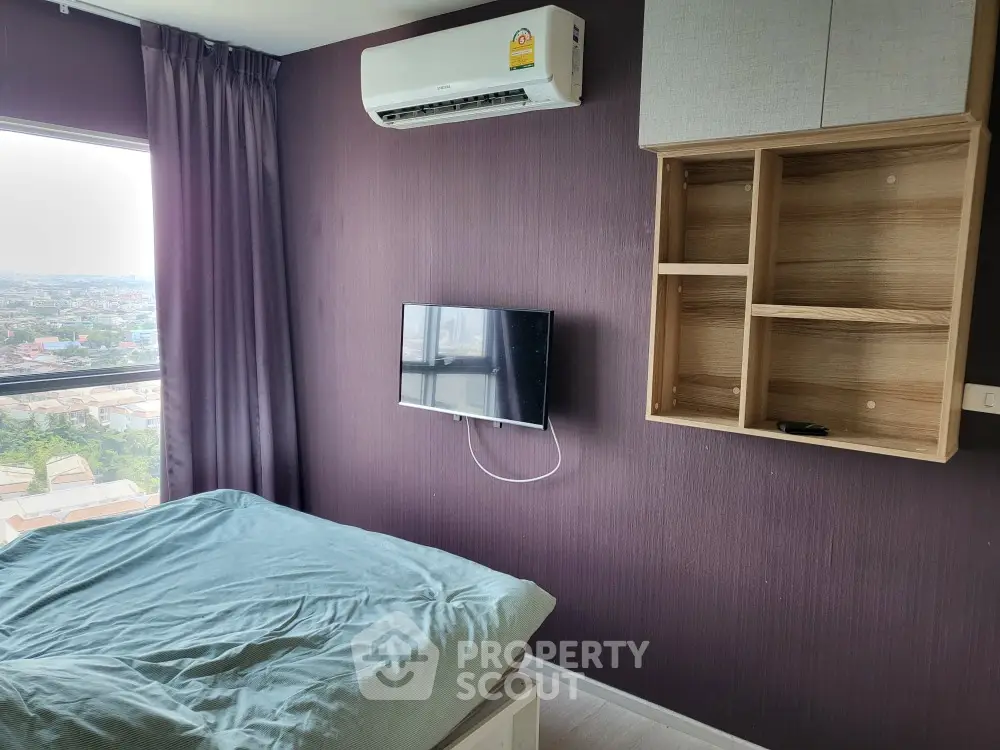 Cozy bedroom with city view, air conditioning, and wall-mounted TV for modern living.