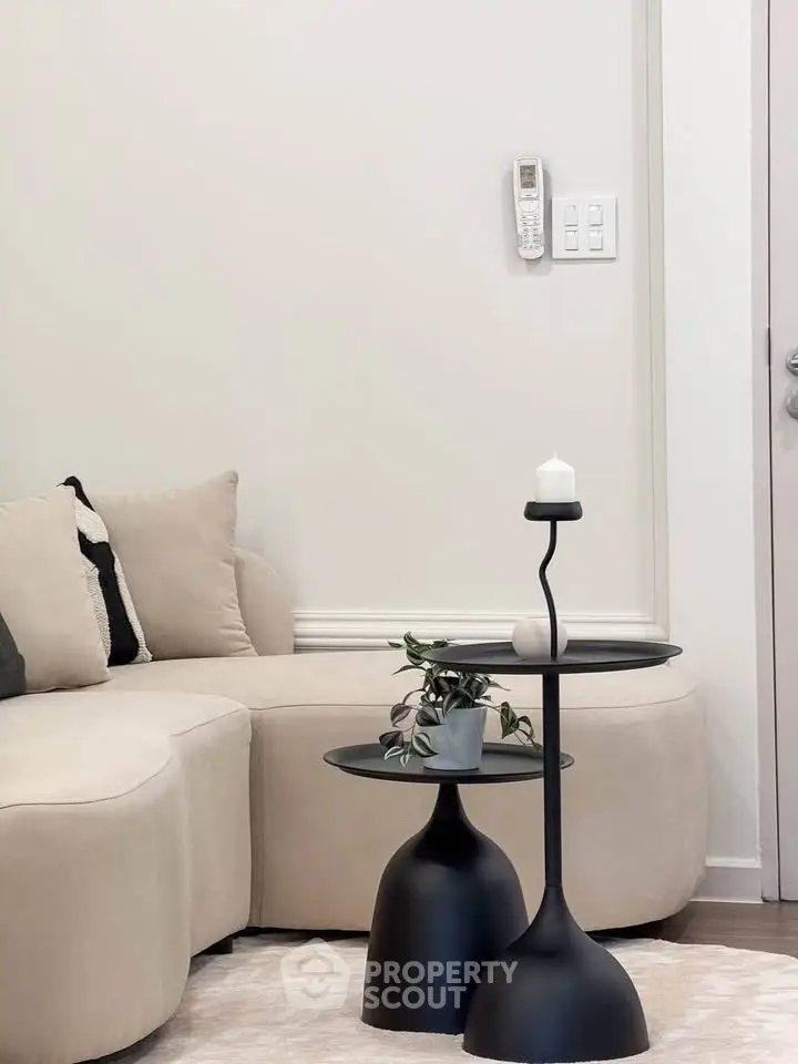 Modern living room with stylish beige sofa and sleek black side tables, perfect for contemporary home decor.