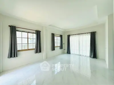 Spacious and bright living room with large windows and elegant curtains in a modern home.