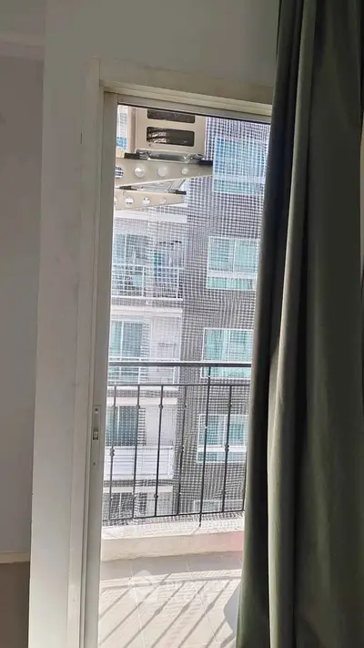 Modern apartment balcony with sliding door and city view, perfect for urban living.