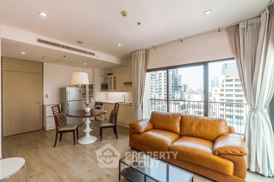 Modern open-plan living room with leather sofa and city view balcony in luxury apartment.