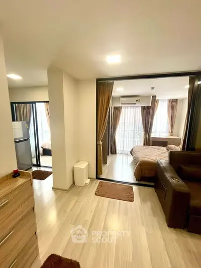 Modern apartment interior with open layout, featuring a cozy living area and bedroom with large windows.