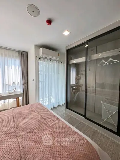 Modern bedroom with large windows, pink bedding, and mirrored wardrobe in a stylish apartment.