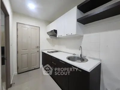 Modern kitchen with sleek cabinetry and stainless steel sink in compact layout.
