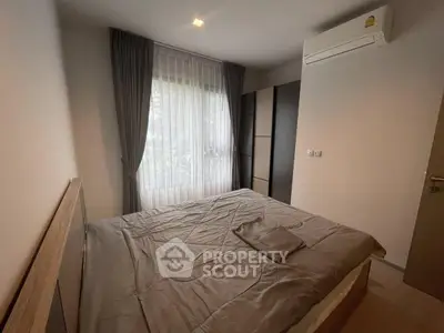 Cozy bedroom with modern furnishings and natural light from large window.