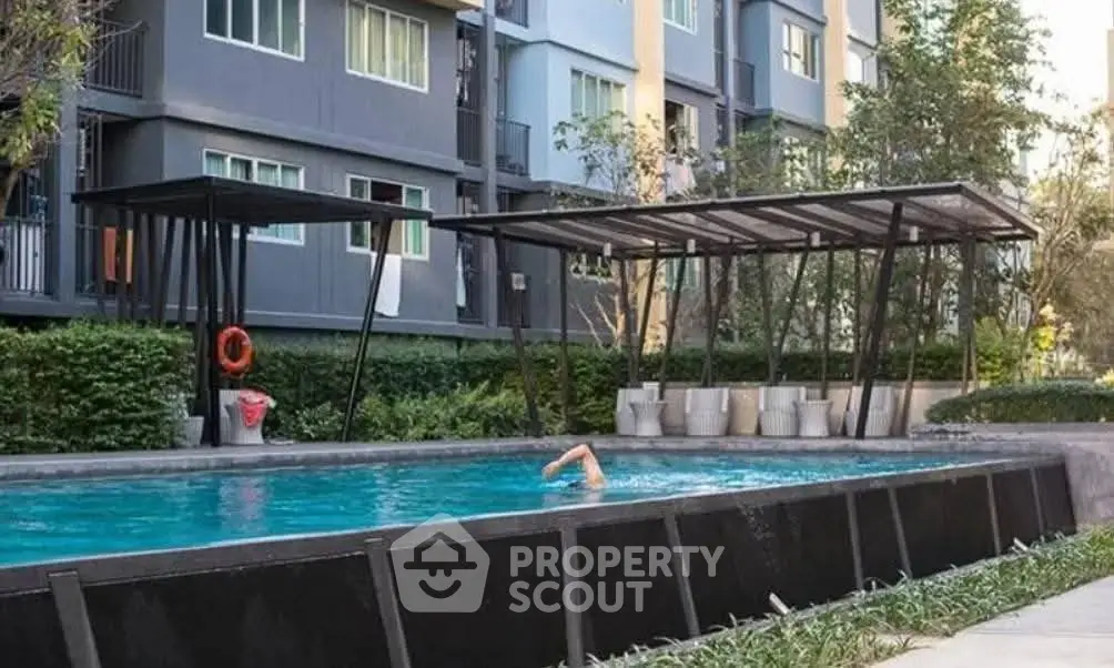 Modern apartment complex with outdoor swimming pool and lush greenery.