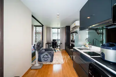 Modern studio apartment with sleek kitchen and cozy living area, featuring hardwood floors and stylish decor.