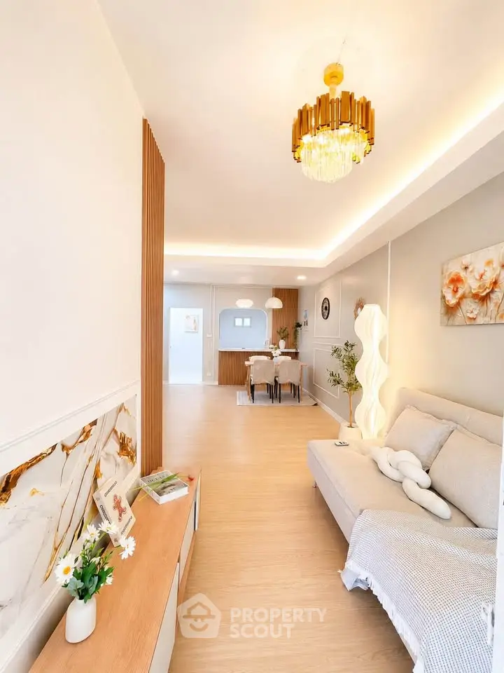 Elegant living room with modern chandelier and cozy decor, showcasing open layout and stylish furnishings.