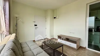 Modern living room with cozy sofa and sleek coffee table, adjacent to a bright kitchen area.