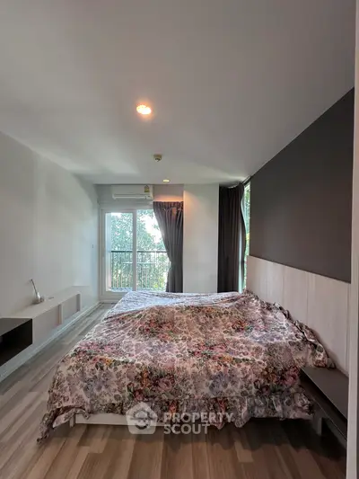 Spacious bedroom with floral bedding and natural light from large window