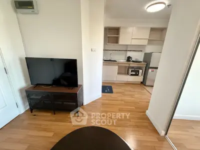 Modern apartment interior with open kitchen and living area, featuring sleek appliances and wooden flooring.