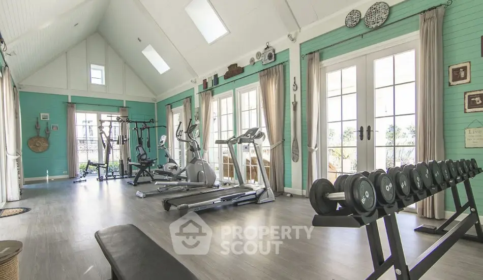 Spacious home gym with modern equipment and large windows for natural light.