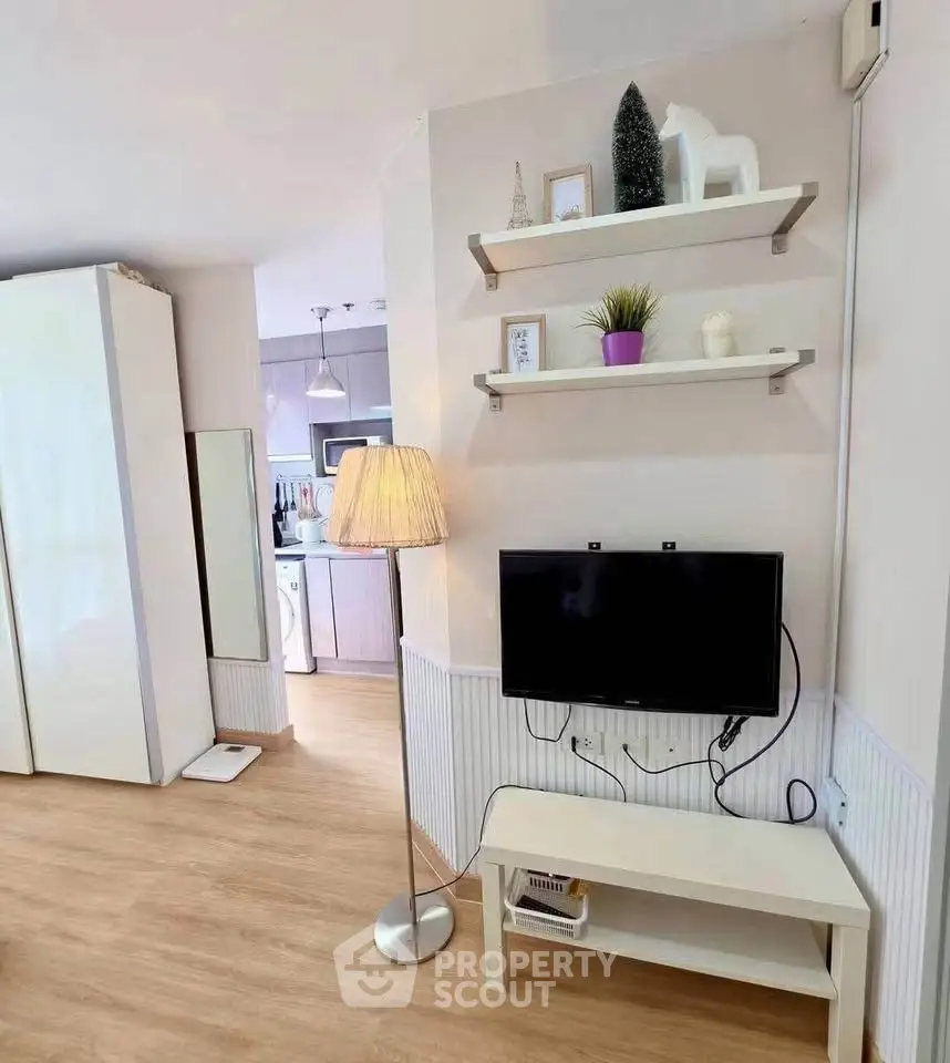 Modern living room with stylish decor and open kitchen layout, featuring a cozy TV area and elegant shelving.