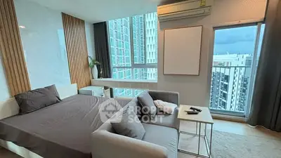 Modern bedroom with large windows and city view, featuring stylish decor and cozy seating area.