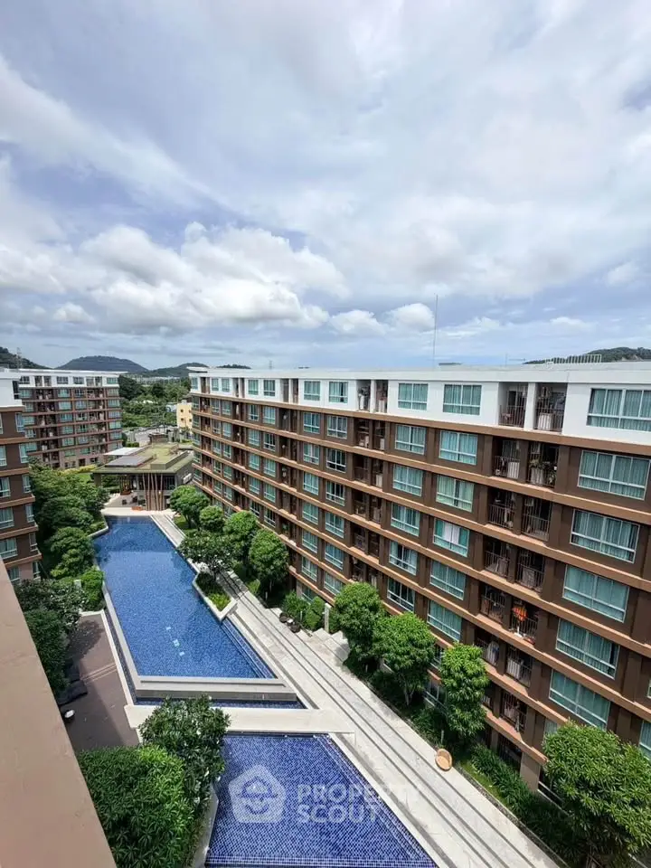 Stunning aerial view of modern apartment complex with luxurious pool and lush greenery, perfect for urban living.