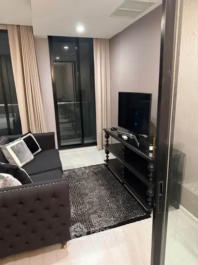 Modern living room with sleek black furniture and large windows in a stylish apartment.