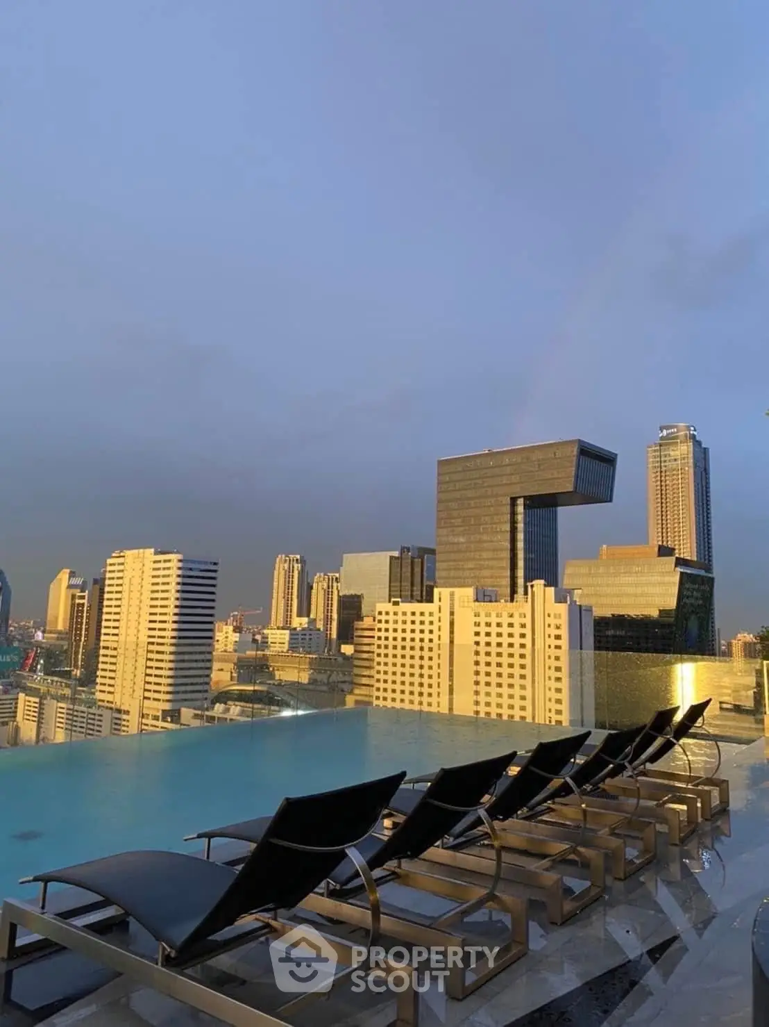 Stunning rooftop pool with city skyline view at sunset, perfect for luxury urban living.