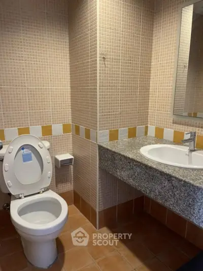 Modern bathroom with tiled walls and granite countertop in real estate property.