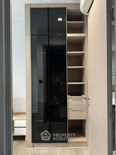 Modern wardrobe with sleek black glass doors and open shelving in a stylish bedroom.